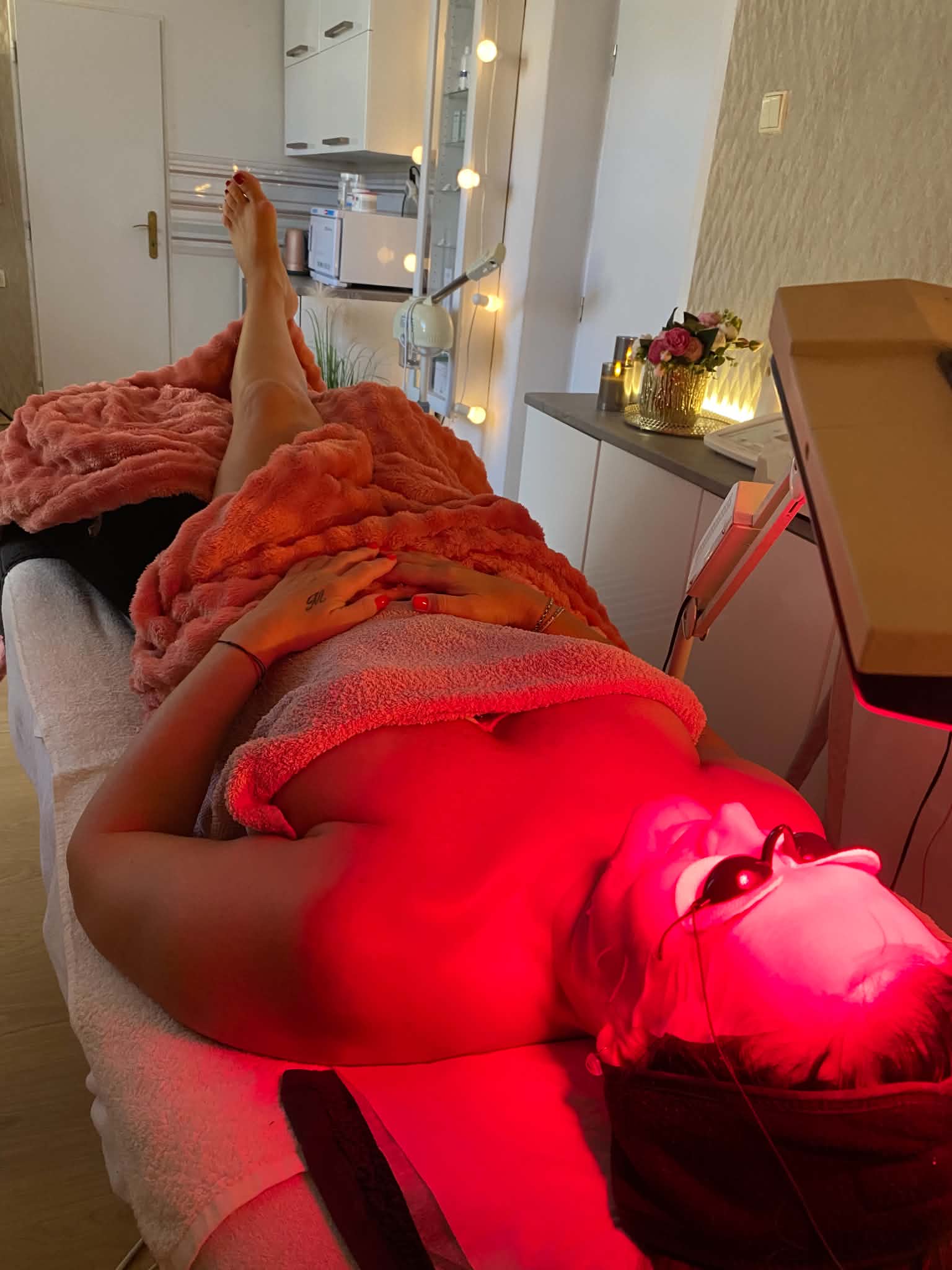 Klientka odpočívá při ošetření v Dermosalonu, nohy podložené polštářem, pod laserovým světlem